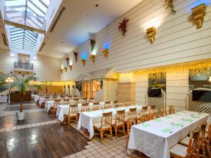 una sala da pranzo con tavoli e sedie bianchi di Airline Hotel a Miyazaki