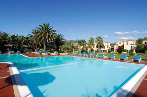 a large swimming pool with blue chairs and palm trees at Apartments in Pula Sardinien Cagliari Provinz 43440 in Foxiʼe Sali