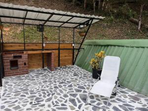 un patio con 2 sillas blancas y chimenea en Entre Verdes Hotel & Glamping, en Medellín