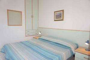 - une chambre avec un lit et une couverture rayée dans l'établissement Holiday Homes in Porto Santa Margherita 43919, à Porto Santa Margherita