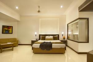 a bedroom with a bed and a chair and a window at Hotel Express Residency Vadodara in Vadodara