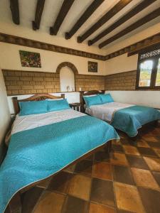 two beds in a room with blue comforters at Posada María del Carmen in Ráquira