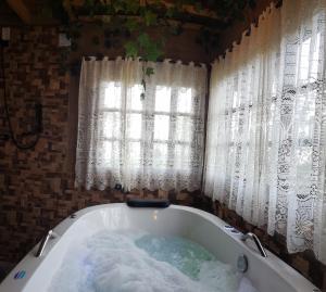 a bath tub filled with water in front of a window at Pousada Grom's Village in Campos do Jordão
