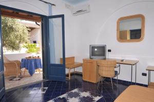 a room with a tv and a desk and a table at Hotel Aura in Vulcano