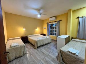 two beds in a room with yellow walls at Alojamientos Premiun Centro in Termas de Río Hondo