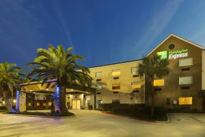 ein Hotelgebäude mit Palmen davor in der Unterkunft Holiday Inn Express Kenner - New Orleans Airport, an IHG Hotel in Kenner