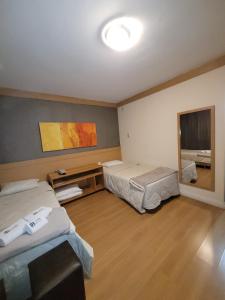 Habitación con 2 camas y espejo. en Studio Living Faria Lima, en São Paulo