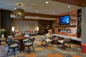 a hotel lobby with tables and chairs and a tv at Courtyard by Marriott Lake George in Lake George