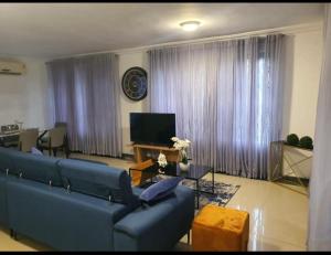 a living room with a blue couch and a television at LV Appartment x Airport Residential Area in Accra