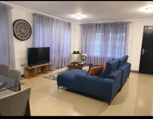 a living room with a blue couch and a tv at LV Appartment x Airport Residential Area in Accra