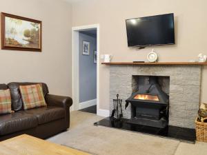 un soggiorno con camino e TV sopra di esso di Barncailzie Lodge a Kirkpatrick Durham