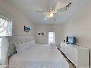 a white bedroom with a bed and a ceiling fan at Bungalows at Seagrove #132 - Kruks Fanta Sea in Seagrove Beach