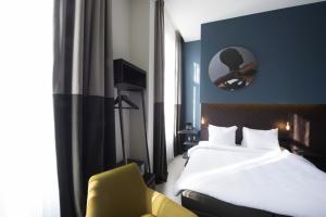 ein Hotelzimmer mit einem Bett und einem gelben Stuhl in der Unterkunft Boutique Hotel Oosteinde in Amsterdam