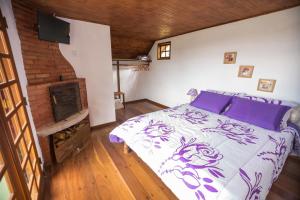 una camera da letto con un letto con cuscini viola e un camino di Pousada do Morro Verde a Carvalhos