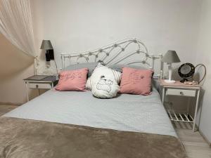 Una cama con almohadas rosas y blancas. en Loft en cantegril, en Punta del Este