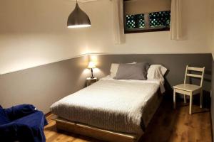 1 dormitorio con 1 cama, 1 silla y 1 lámpara en Belle maison avec vue sur la rivière, en L'Anse-Saint-Jean