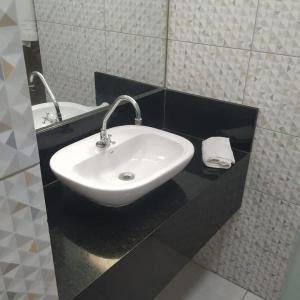 y baño con lavabo blanco y espejo. en Bahia Flat localização excelente, en Salvador