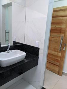 y baño con lavabo blanco y espejo. en Bahia Flat localização excelente, en Salvador