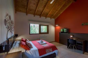 1 dormitorio con paredes de color naranja, 1 cama y escritorio en Solar Selvana - Casas de montaña en Villa La Angostura