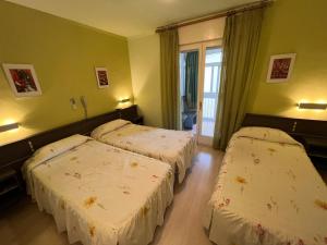 2 camas en una habitación con paredes verdes en Hostal La Vila, en Olot