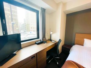 a hotel room with a desk and a large window at Smile Hotel Premium Sapporo Susukino in Sapporo