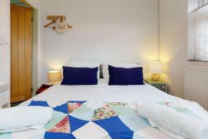 1 dormitorio con 1 cama grande con almohadas azules en Cobweb Cottage en Waenfawr
