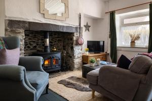 sala de estar con 2 sillas y chimenea en Cobweb Cottage en Waenfawr