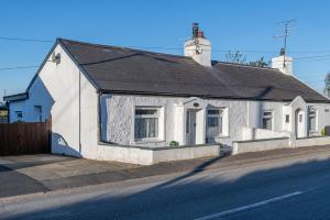 una casa blanca al lado de una calle en Cobweb Cottage en Waenfawr