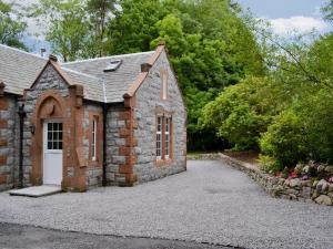 uma pequena casa de pedra com uma entrada em Barncailzie Lodge em Kirkpatrick Durham