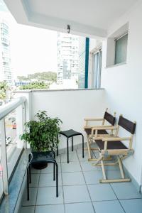 een balkon met 2 stoelen en een tafel bij Praia da Costa 2 Quartos com Suite Clássico in Vila Velha
