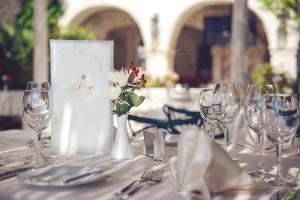 a table with glasses and a vase with flowers on it at Hotel Azimut in Sveti Stefan