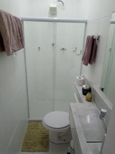 a white bathroom with a shower and a toilet at Suíte próxima ao Porto da Barra in Salvador