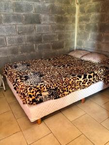 Una cama con una manta de leopardo encima. en hermosa cabaña cerca del puerto en San Clemente del Tuyú