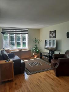 a living room with a couch and a tv at Auberge le Petit Séjour in Chateau Richer