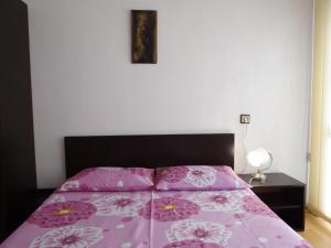 Una cama con colcha púrpura con flores. en Apartment Friends, en Sandanski