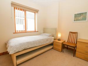 een slaapkamer met een bed, een stoel en een raam bij Arwelfa in Valley