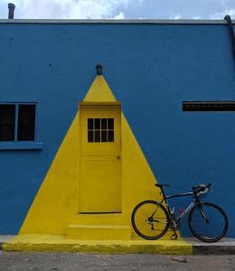 a bike parked next to a building with a yellow door at Ragamuffin Hostel in Kingston