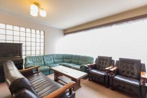 a living room with leather couches and a tv at Sakurajima Seaside Hotel in Sakurajima