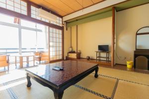 ein Wohnzimmer mit einem Tisch und einem großen Fenster in der Unterkunft Sakurajima Seaside Hotel in Sakurajima