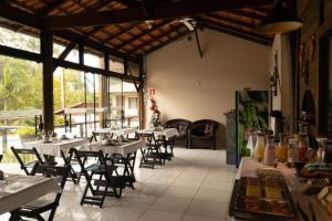 uma sala de jantar com mesas, cadeiras e janelas em Pousada Beira Mar na Ilha do Mel