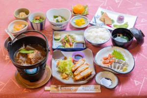 einen Tisch mit Teller mit Lebensmitteln und Schüsseln mit Lebensmitteln in der Unterkunft Sakurajima Seaside Hotel in Sakurajima