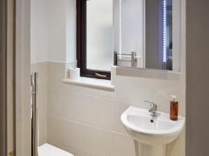 a white bathroom with a sink and a mirror at The Garden Apartment in Saint Columb Major