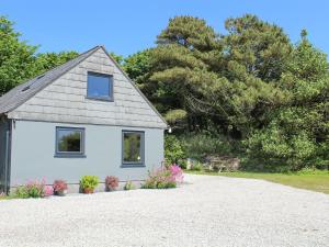 a small white house with a gravel driveway at The Garden Apartment in Saint Columb Major