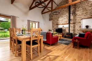 a living room with a table and chairs and a fireplace at Threshing Barn at East Trenean Farm -Stunning Cornish Cottage sleeping 6 with hot tub, private garden, rural views and EV facilities in East Looe