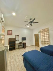 1 dormitorio con 1 cama azul y ventilador de techo en Cenang Room Rahsia Motel en Pantai Cenang