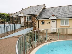 a house with a fence around a swimming pool at 9 Porth Veor Villas in Saint Columb Minor