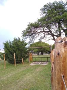 a wooden post with a fence and a tree at El Trébol Casa de Campo in Naicó