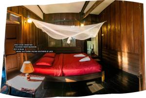 a bedroom with a red bed with a mosquito net at Pomelo Restaurant and Guesthouse- Serene Bliss, Life in the Tranquil Southend of Laos in Ban Khon