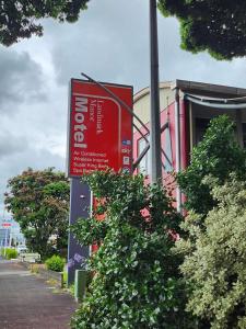 a red sign in front of a building with bushes at Landmark Manor in New Plymouth