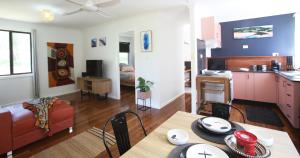 a kitchen and a living room with a table and chairs at Sea Foam Cottage in Corindi